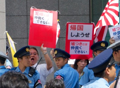Anti-foreigner protesters hold signs calling for foreigners to leave the country.